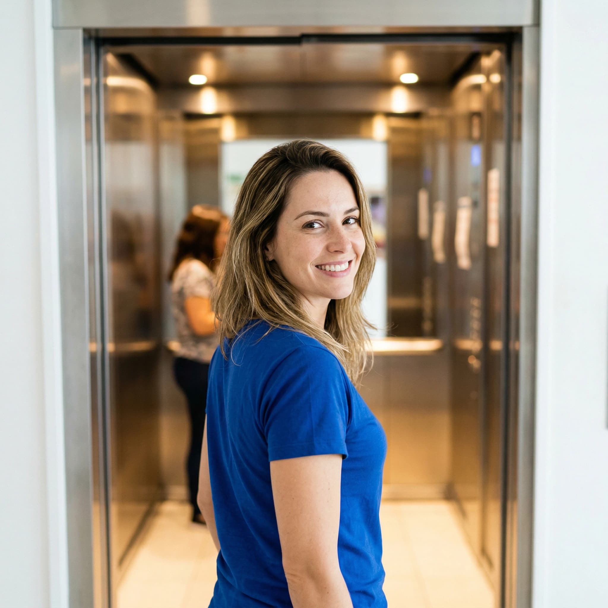 Cliente satisfeita em frente a um elevador IZ recém-instalado.